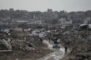 A car drives along a muddy road amid destroyed buildings in the Sheikh Radwan neighborhood of Gaza City, Friday, Nov. 14, 2025. (AP Photo/Jehad Alshrafi)