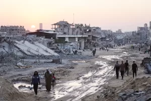 Palestinians walk among destroyed buildings in Khan Younis, southern Gaza Strip, Sunday, Nov. 2, 2025. (AP Photo/Jehad Alshrafi)