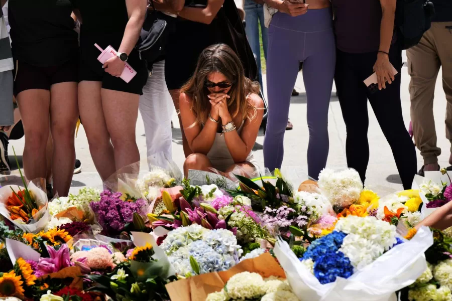 A woman kneels and prays at a flower memorial to shooting victims outside the Bondi Pavilion at Sydney’s Bondi Beach, Monday, Dec. 15, 2025, a day after a shooting. (AP Photo/Mark Baker)