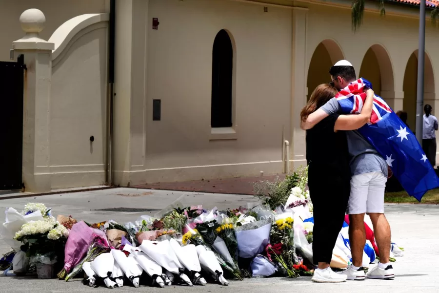 A couple lay flowers at a tribute to shooting victims outside the Bondi Pavilion at Sydney’s Bondi Beach, Monday, Dec. 15, 2025, a day after a shooting. (AP Photo/Mark Baker)