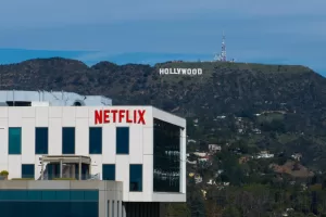 A Netflix sign is displayed atop a building in Los Angeles, Thursday, Dec. 18, 2025, with the Hollywood sign in the distance. (AP Photo/Jae C. Hong)