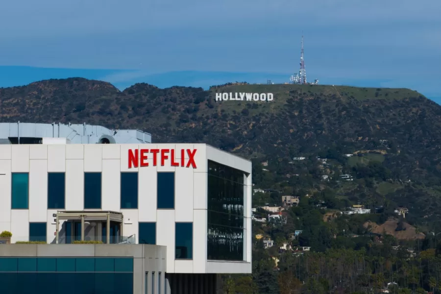 A Netflix sign is displayed atop a building in Los Angeles, Thursday, Dec. 18, 2025, with the Hollywood sign in the distance. (AP Photo/Jae C. Hong)