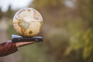A closeup shot of a person holding bible with desk globe on top with a blurred background A closeup shot of a person holding bible with desk globe on top with a blurred background