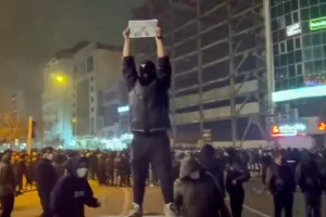In this frame grab from video obtained by the AP outside Iran, a masked demonstrator holds a picture of Iran’s Crown Prince Reza Pahlavi during a protest in Tehran, Iran, Friday, January. 9, 2026. (UGC via AP)