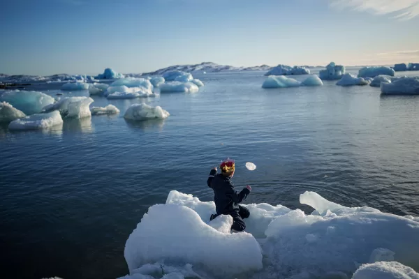 A boy throws ice into the sea in Nuuk, Greenland, March 11, 2025. (AP Photo/Evgeniy Maloletka, File)