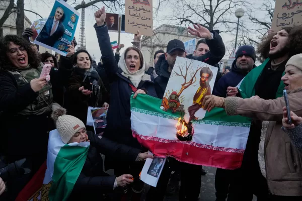Protesters burn the Iranian national flag during a rally in support of the nationwide mass demonstrations in Iran against the government in Paris, Sunday, Jan. 11, 2026. (AP Photo/Michel Euler)