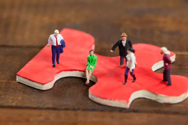 Conceptual image of miniature people on a jigsaw puzzle