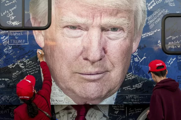 FILE – Supporters of Republican presidential nominee former President Donald Trump sign a bus before a campaign rally at the Butler Farm Show, Oct. 5, 2024, in Butler, Pa. (AP Photo/Julia Demaree Nikhinson, File)