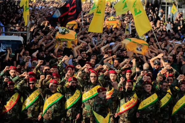 Hezbollah fighters raise their fists and chant slogans as they march in the funeral procession of five comrades killed in Israeli strikes in recent days, in the southern town of Nabatieh, Lebanon, Sunday, Nov. 2, 2025. (AP Photo/Mohammad Zaatari)