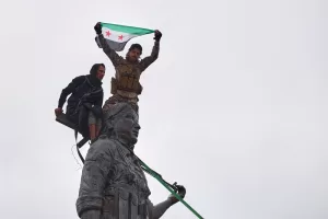 Syrian government soldiers wave a Syrian flag after climbing atop a statue of a female Kurdish fighter, following the takeover of the town from U.S.-backed Syrian Democratic Forces (SDF) during an ongoing push against Kurdish-led forces, in Tabqa, eastern Syria, Sunday, Jan. 18, 2026. (AP Photo/Omar Albam) Syrian government soldiers wave a Syrian flag after climbing atop a statue of a female Kurdish fighter, following the takeover of the town from U.S.-backed Syrian Democratic Forces (SDF) during an ongoing push against Kurdish-led forces, in Tabqa, eastern Syria, Sunday, Jan. 18, 2026. (AP Photo/Omar Albam)