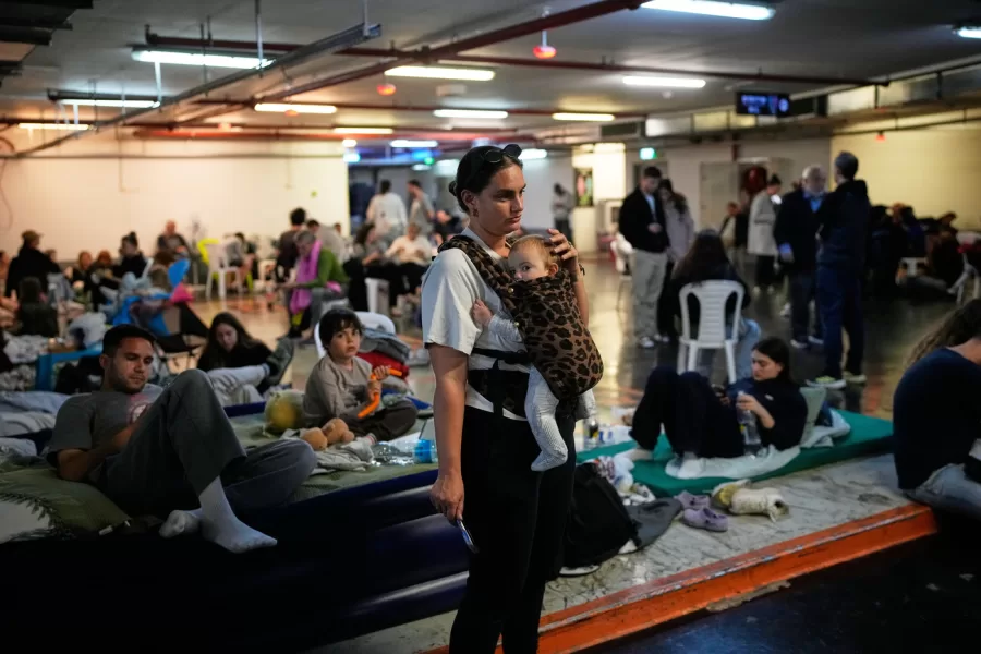 Leah Guttmann holds her son, Teddy, as other people take shelter in an underground parking garage while air-raid sirens warn of incoming missiles launched by Iran toward Tel Aviv, Israel, Sunday, March 1, 2026. (AP Photo/Ohad Zwigenberg)