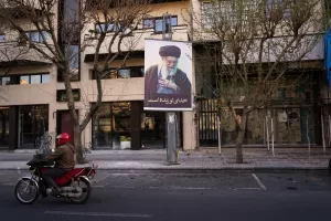 A motorcycle drives past a picture of the late Iranian Supreme Leader Ayatollah Ali Khamenei along an empty street in Tehran, Iran, Sunday, March 1, 2026, following the confirmed death of Khamenei in U.S. and Israeli strikes. (AP Photo/Vahid Salemi)