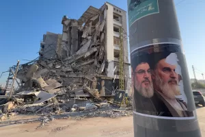 Portraits of late Hezbollah leader Sayyed Hassan Nasrallah and the late Iranian revolutionary founder Ayatollah Khomeini, are seen in front of a destroyed building that housed a branch of Al-Qard Al-Hassan, a non-bank financial institution run by Hezbollah, which was hit by an Israeli airstrike in Dahiyeh, Beirut’s southern suburbs, Lebanon, Tuesday, March 10, 2026. (AP Photo/Hussein Malla)