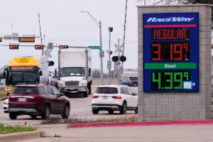 Drivers navigate a busy intersection past a sign displaying the current gas prices at a filling station in Plano, Texas, Friday, March 6, 2026. (AP Photo/Tony Gutierrez)