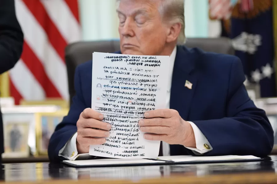 President Donald Trump holds papers in the Oval Office of the White House before signing an executive order Tuesday, March 31, 2026, in Washington. (AP Photo/Alex Brandon)