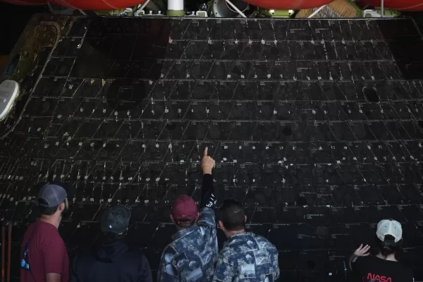 People point at different shields on NASA’s Artemis II capsule aboard the USS John P. Murtha at Naval Base San Diego Saturday, April 11, 2026, in San Diego. (AP Photo/Gregory Bull)