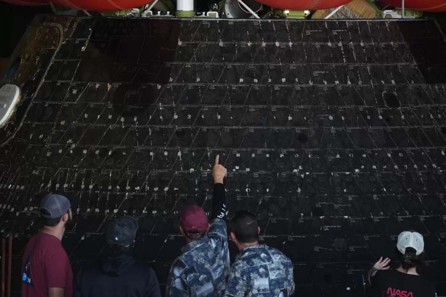 People point at different shields on NASA’s Artemis II capsule aboard the USS John P. Murtha at Naval Base San Diego Saturday, April 11, 2026, in San Diego. (AP Photo/Gregory Bull)