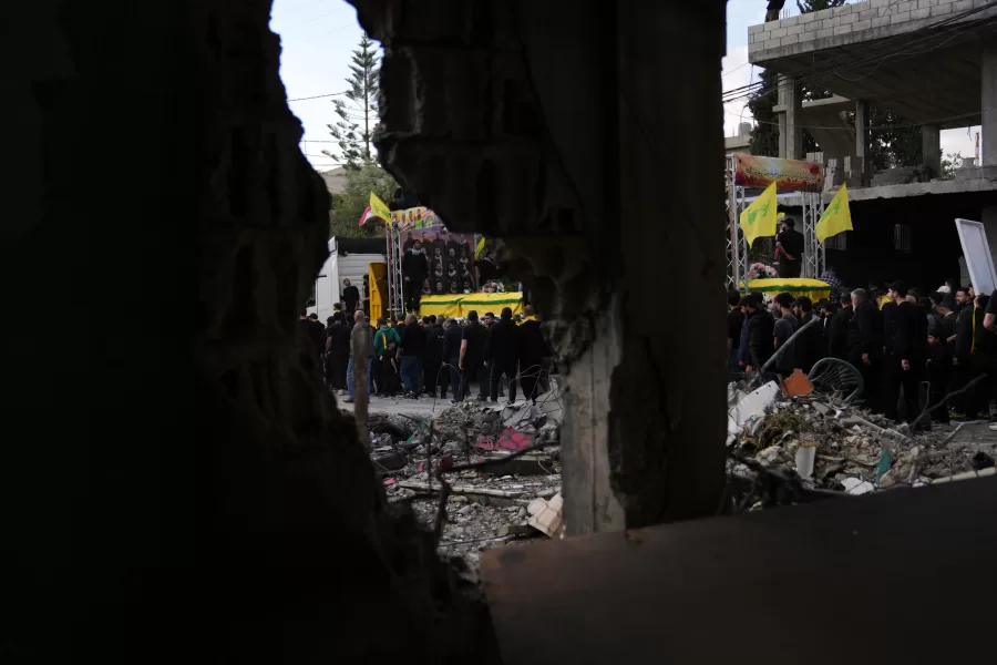 A semi transporting coffins that contain the remains of Hezbollah fighters who were killed before the ceasefire in the war between Hezbollah and Israel, drives past the rubble of a destroyed building, as part of a mass funeral procession in the southern village of Kfar Sir, Lebanon, Tuesday, April 21, 2026. (AP Photo/Hassan Ammar)