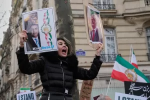 A protester holds posters of Reza Pahlavi during a rally in support of the nationwide mass demonstrations in Iran against the government in Paris, Sunday, Jan. 11, 2026. (AP Photo/Michel Euler)