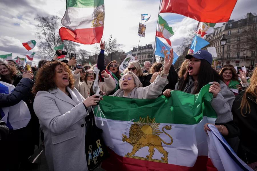 A woman opens a bottle of Champagne during a demonstration in reaction to the U.S. and Israeli strikes on Iran on Sunday, March 1, 2026, in Paris, France. (AP Photo/Aurelien Morissard)