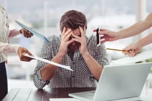Stressed man frustrated with electronic devices in office Stressed man frustrated with electronic devices in office
