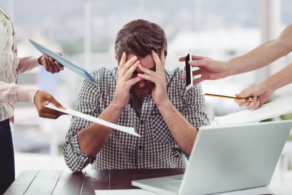 Stressed man frustrated with electronic devices in office Stressed man frustrated with electronic devices in office