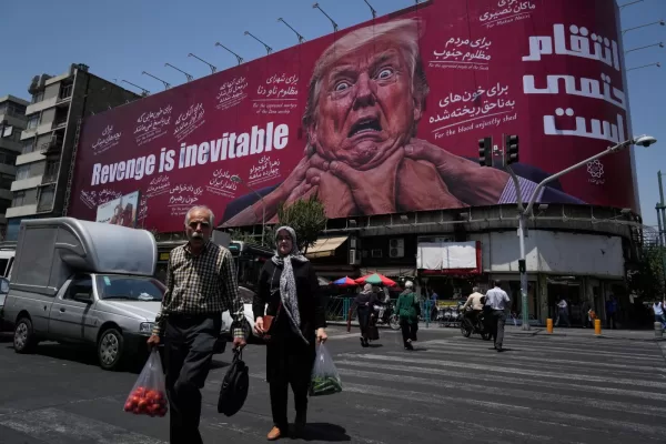 Pedestrians walk past a billboard depicting U.S. President Donald Trump being grabbed by the neck alongside the message “Revenge is inevitable” in English and Farsi, in Tehran, Iran, Monday, July 27, 2026. (AP Photo/Vahid Salemi)