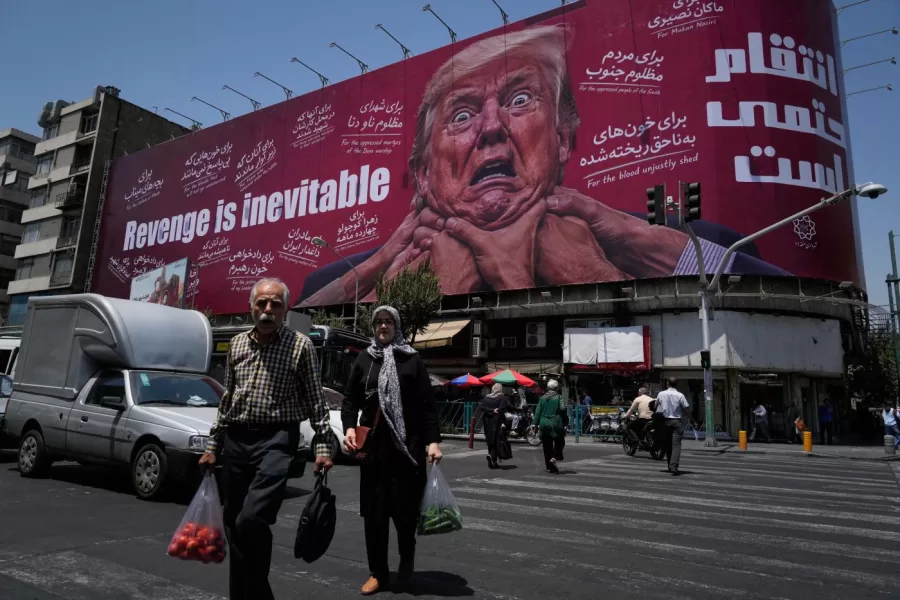 Pedestrians walk past a billboard depicting U.S. President Donald Trump being grabbed by the neck alongside the message “Revenge is inevitable” in English and Farsi, in Tehran, Iran, Monday, July 27, 2026. (AP Photo/Vahid Salemi)