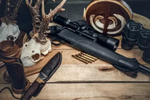 Retro hunting ammunition of rifle and binoculars. Delicious sausage and brown bread on a wooden table. Retro hunting ammunition of rifle and binoculars. Delicious sausage and brown bread on a wooden table.
