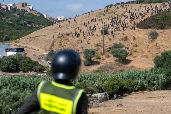 A member of Moroccan security stands guard as migrants gather on a hill attempting to cross from the border town of Fnideq to the Spanish enclave of Ceuta, Saturday, Aug. 15, 2026. (AP Photo) A member of Moroccan security stands guard as migrants gather on a hill attempting to cross from the border town of Fnideq to the Spanish enclave of Ceuta, Saturday, Aug. 15, 2026. (AP Photo)