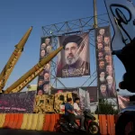 Motorbikes drive past Iranian missiles and banners showing portraits of the Iranian Supreme Leader Ayatollah Mojtaba Khamenei, center, and the late armed forces commanders and nuclear scientists, who were killed in Israeli and U.S. strikes, displayed in a military exhibition commemorating the anniversary of the start of the 1980-88 Iraq-Iran war at Baharestan Square, in Tehran, Monday, Sept. 28, 2026. (AP Photo/Vahid Salemi)